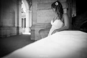 Femme pensive en robe blanche avec une fleur dans les cheveux sous une arche. © Reflets Du Ciel