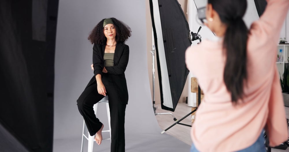Modèle en tailleur noir posant pour une séance photo professionnelle en studio avec éclairages.